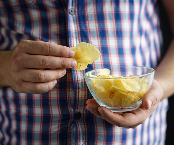 Overweight gentleman with bowl of crisps