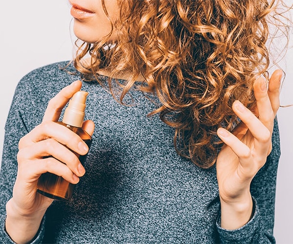 Girl spraying product on hair